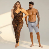 A woman wearing a black and orange leaf patterned plus size pajama set with lace trim for comfortable confident wear