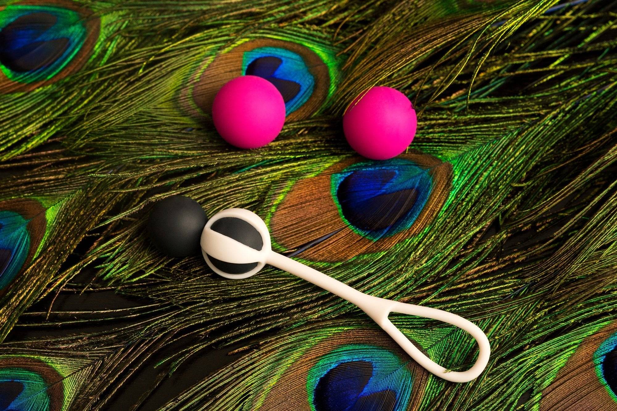 A sleek white and black silicone massager with a looped handle and two vibrant pink spheres for adult pleasure.