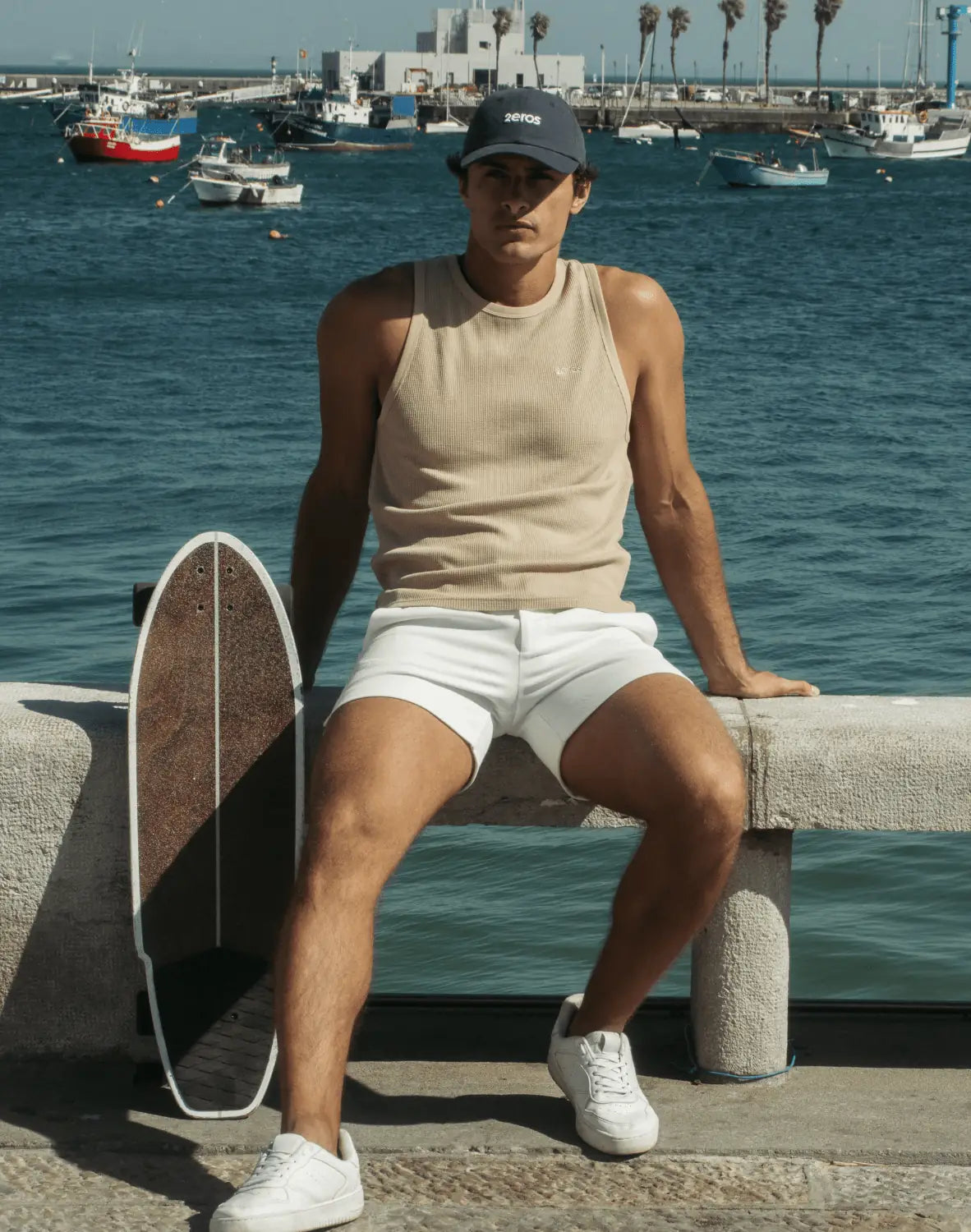 Beige ribbed knit tank top with a small white chest logo featured in a 2026 guide to tops styles and fabrics