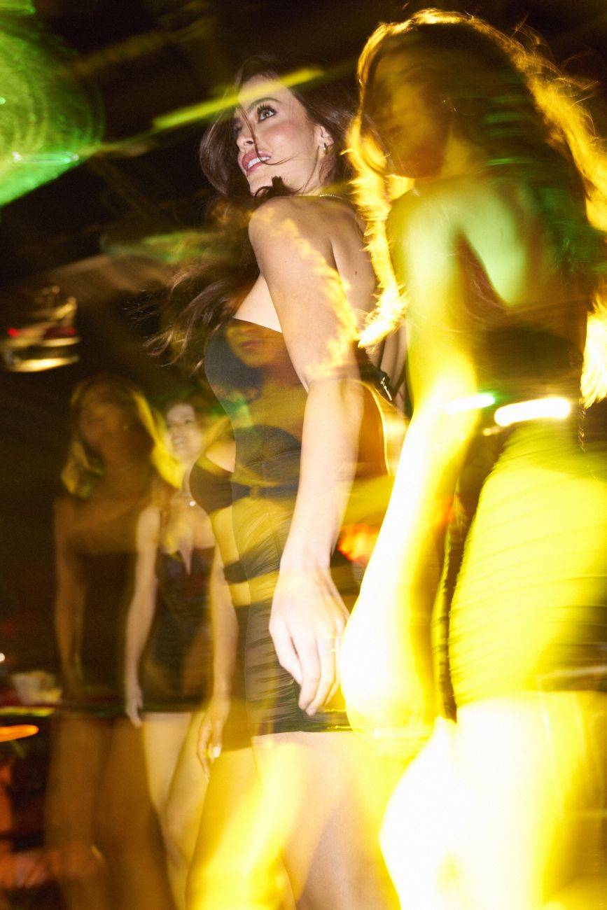 A woman dancing in a black and yellow striped sheer fabric dress under vibrant green and gold stage lights.