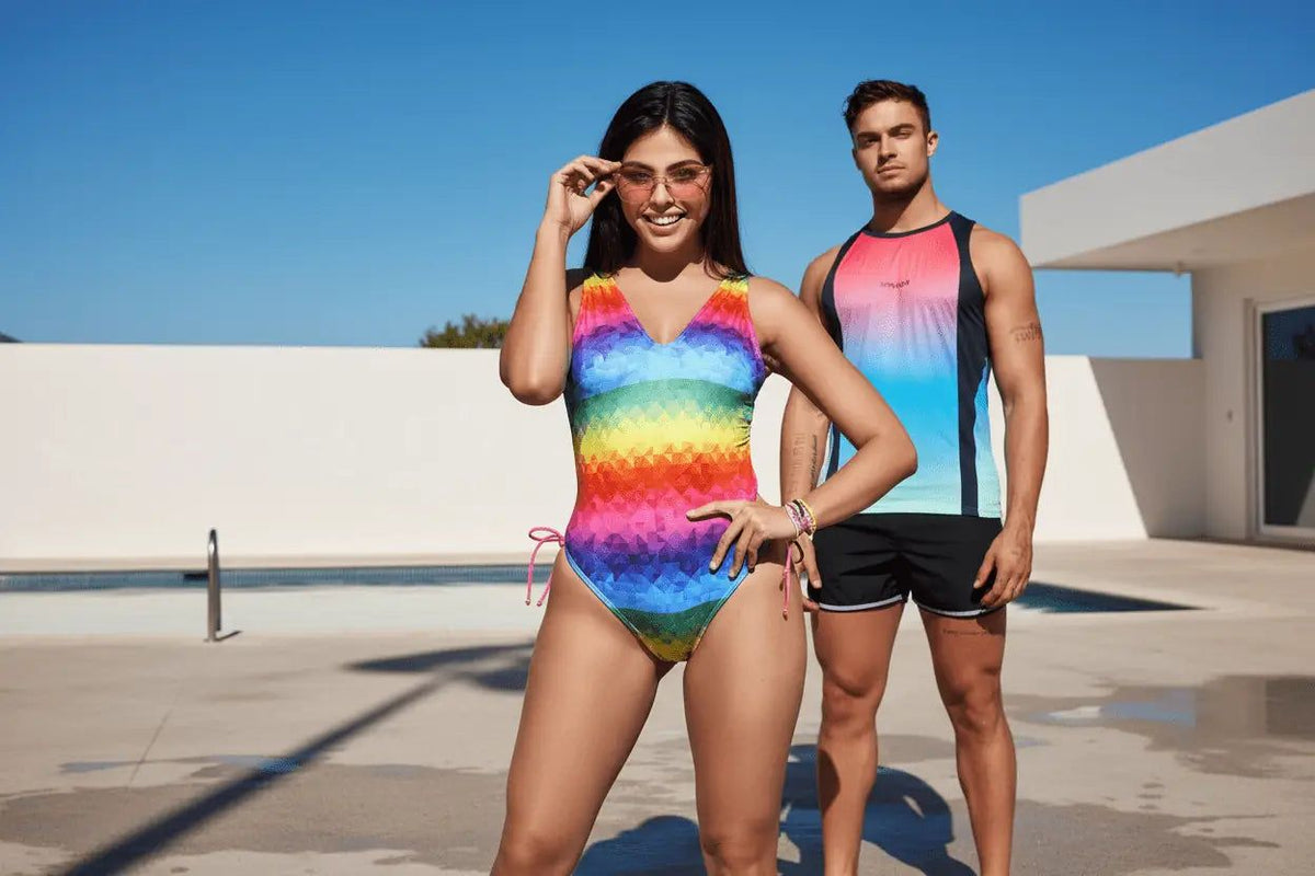 Rainbow-colored geometric patterned one-piece swimsuit with pink tie-side strings for pride and rave wear confidence.