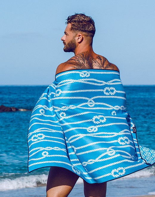 Blue towel with white rope knot pattern wrapped around a man’s shoulders in towels collection