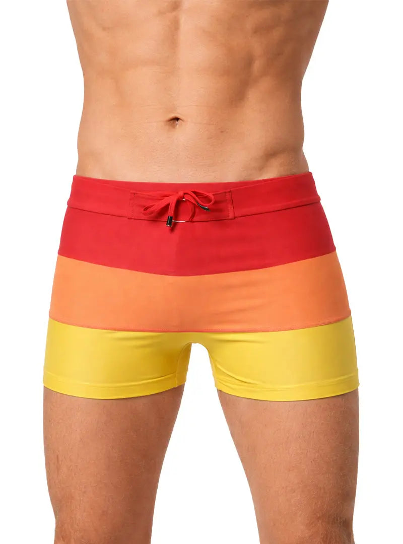 Torso of a man wearing tricolour red, orange, and yellow swimming shorts.