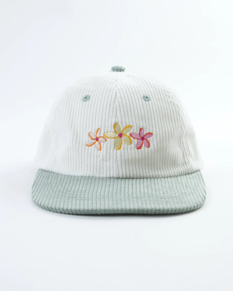 White corduroy baseball cap with sage brim, featuring embroidered flowers, against white.