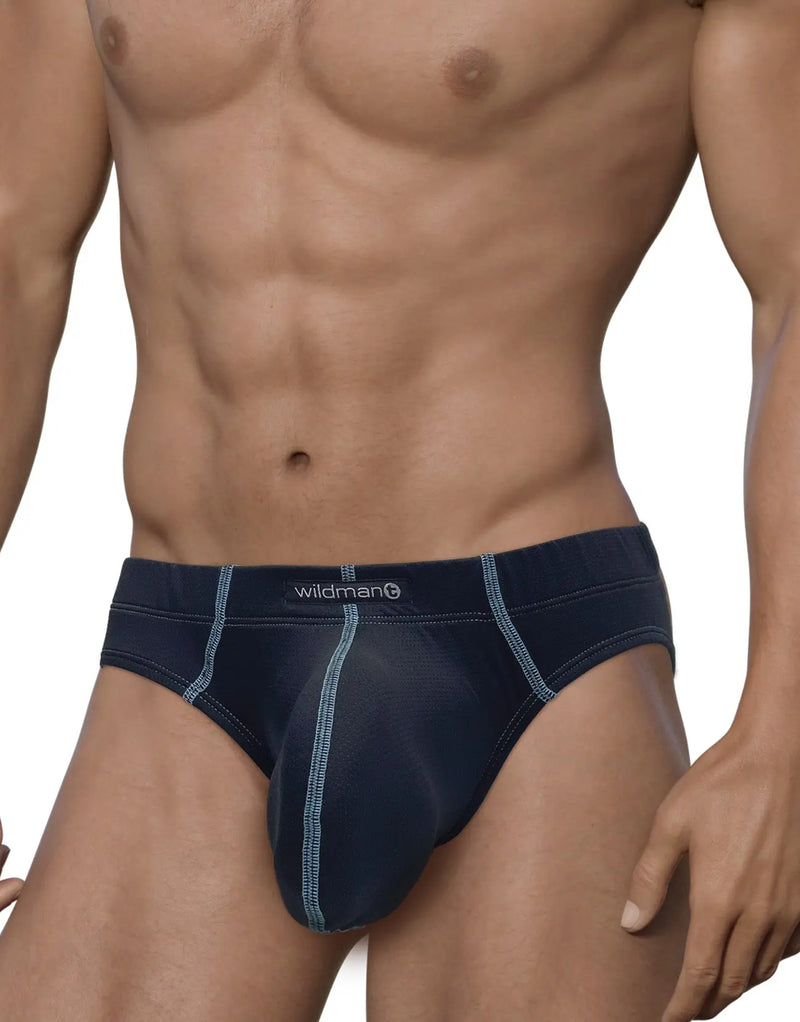 Muscular man standing against plain white background wearing dark blue briefs.