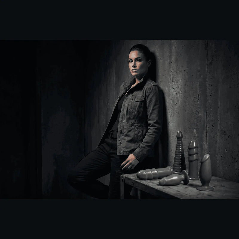 Confident woman with American Bombshell gunmetal grey anal toys in a dark, moody editorial lifestyle setting.