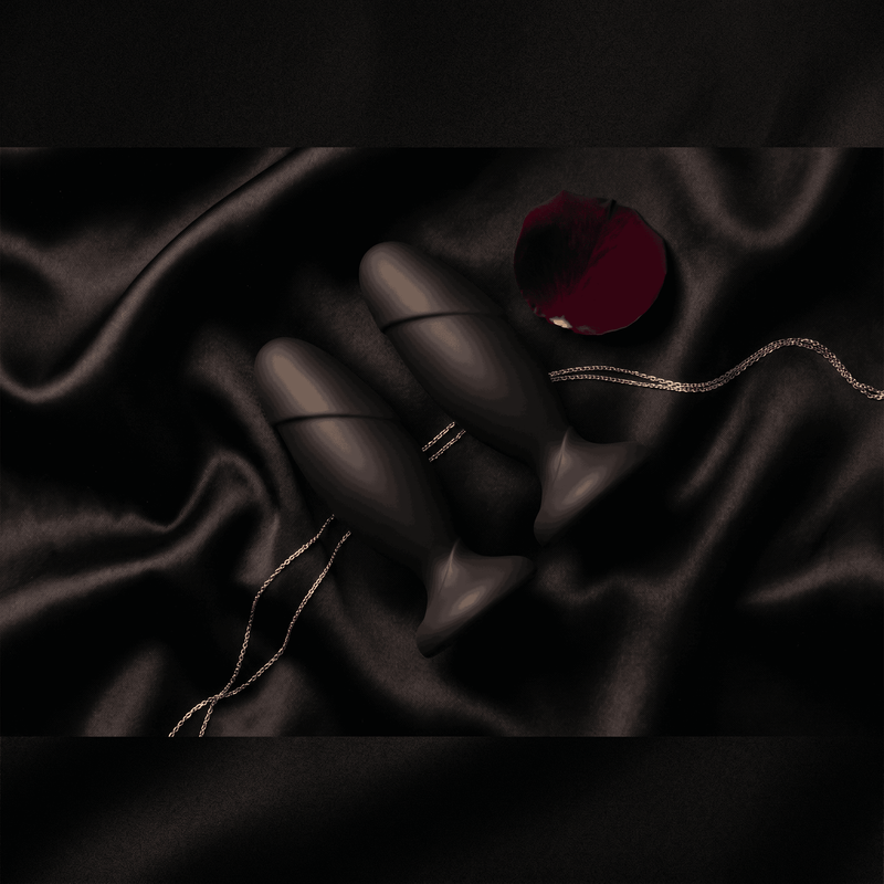 Anal Adventures black silicone anal plugs on black satin with rose petal, dark luxury editorial flat lay