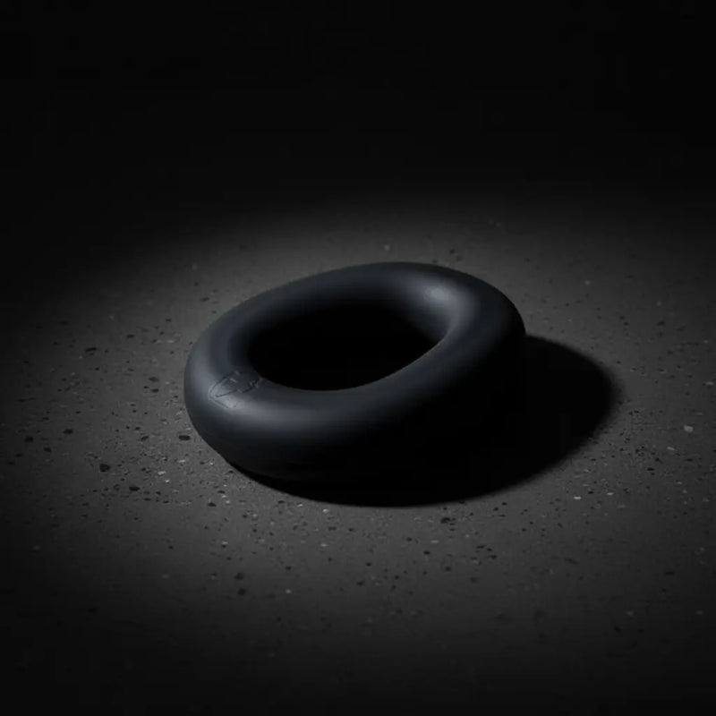 Brutus Sex Toys cock ring showcased in a dramatic low-light setting, highlighting its sleek design and premium material.