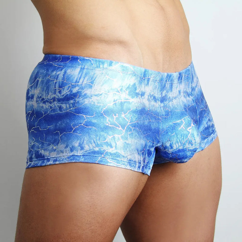 A man wearing blue and white patterned low-rise trunks against background.