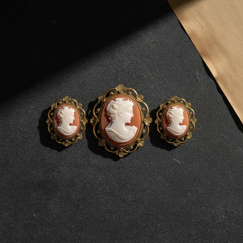 Three antique cameo brooches featuring carved profiles resting on dark slate.