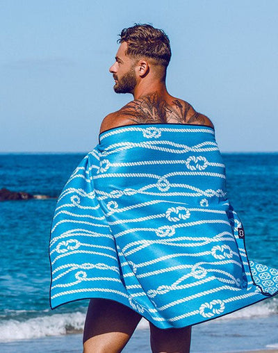 Blue towel with white rope knot pattern wrapped around a man’s shoulders in towels collection