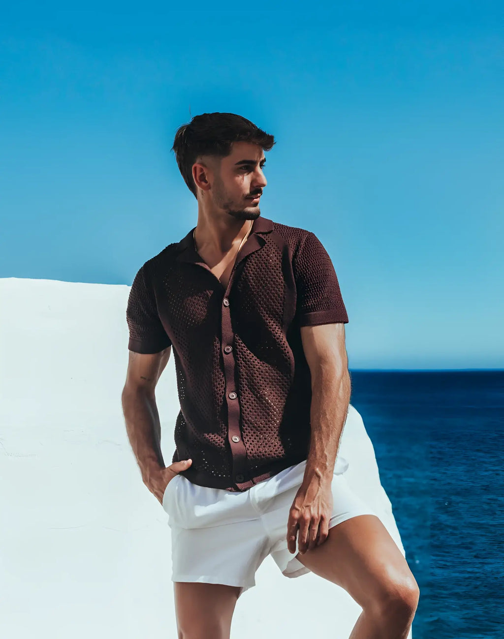 A man wearing a 2EROS Amalfi shirt carbon black short sleeved textured knit button up with white shorts