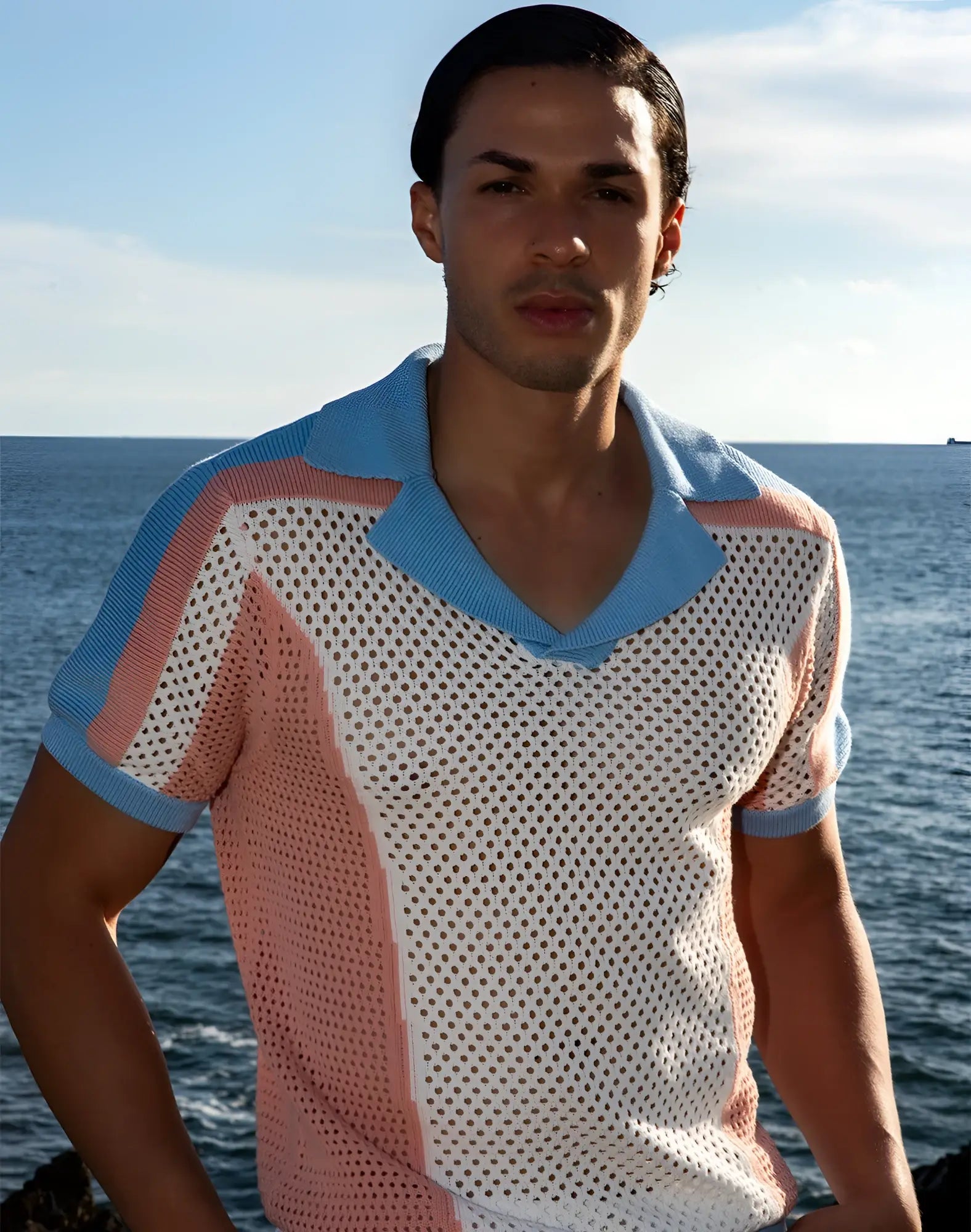 A man wearing a 2EROS Aruba polo short-sleeved v-neck knit shirt with white mesh body and pink blue accents