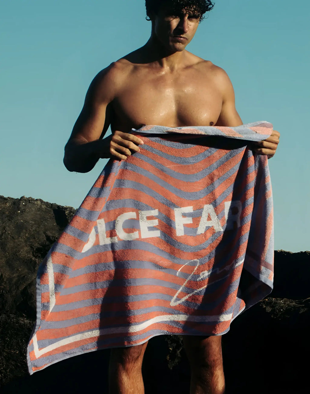 2eros beach towel in orange and blue stripes with white dolce far lettering and signature on soft cotton fabric