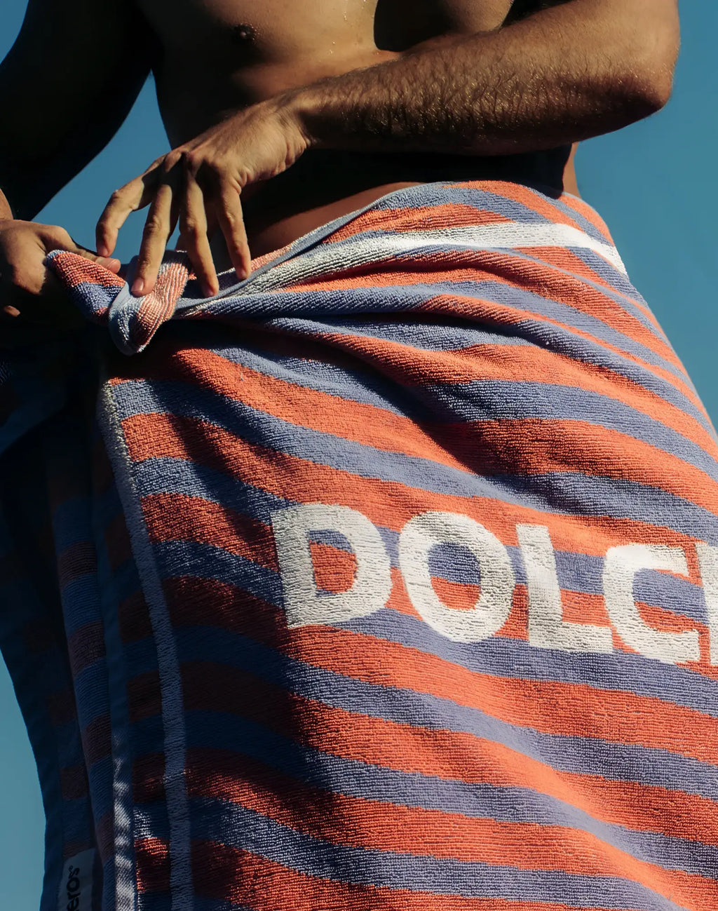 2eros beach towel in vibrant orange and blue stripes with bold white dolce lettering made of soft cotton fabric
