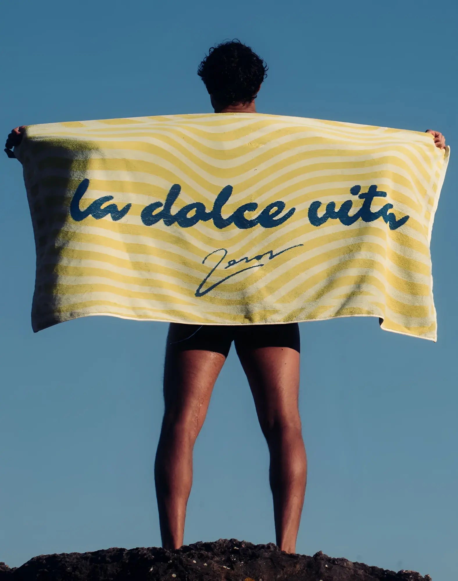 2EROS beach towel in yellow and white stripes with blue la dolce vita cursive print for beach use