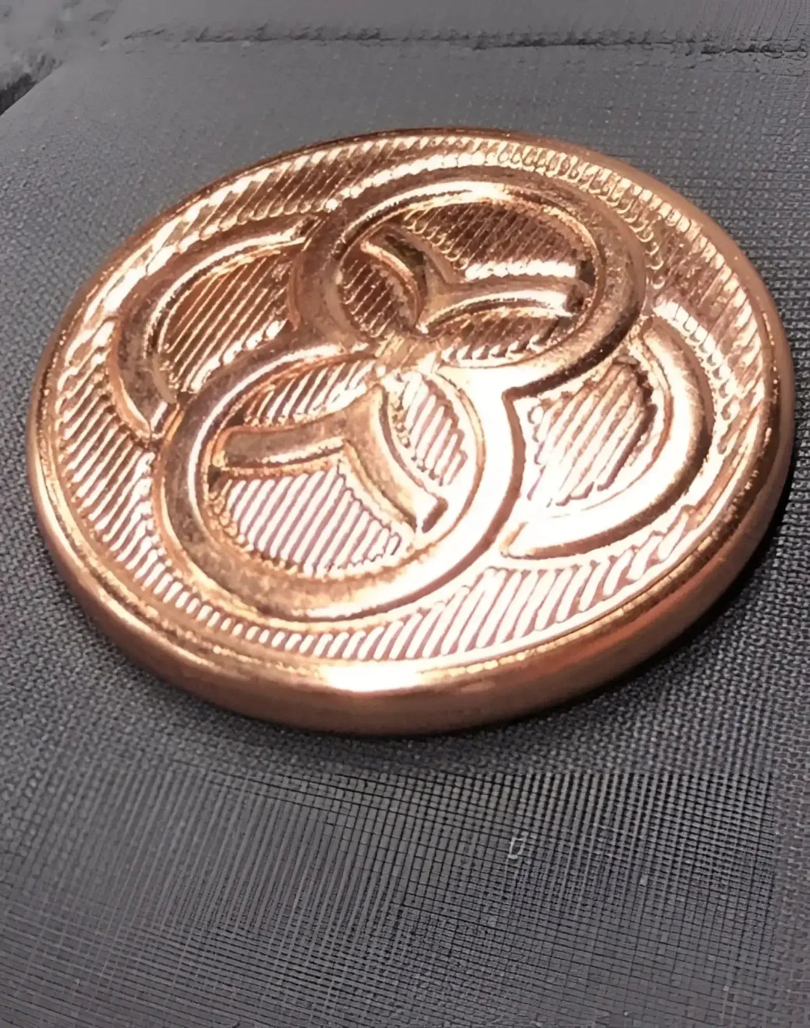 A round copper-toned metal button with a three-leaf clover and diagonal texture on 2eros bondi shorts alloy