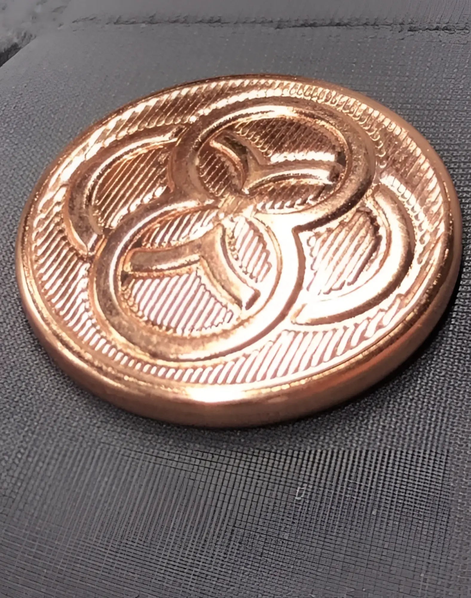 A round copper-toned metal button with a three-leaf clover and diagonal texture on 2eros bondi shorts alloy