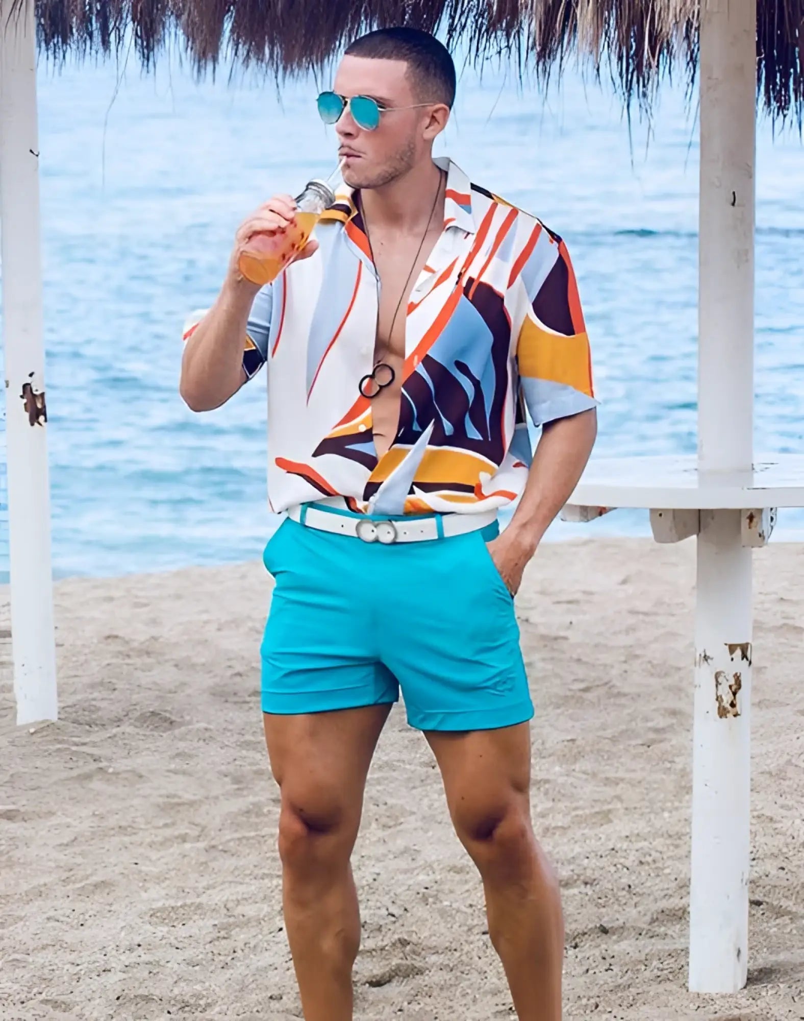 Man wearing vibrant abstract patterned short-sleeve shirt paired with aqua 2eros bondi shorts series 3