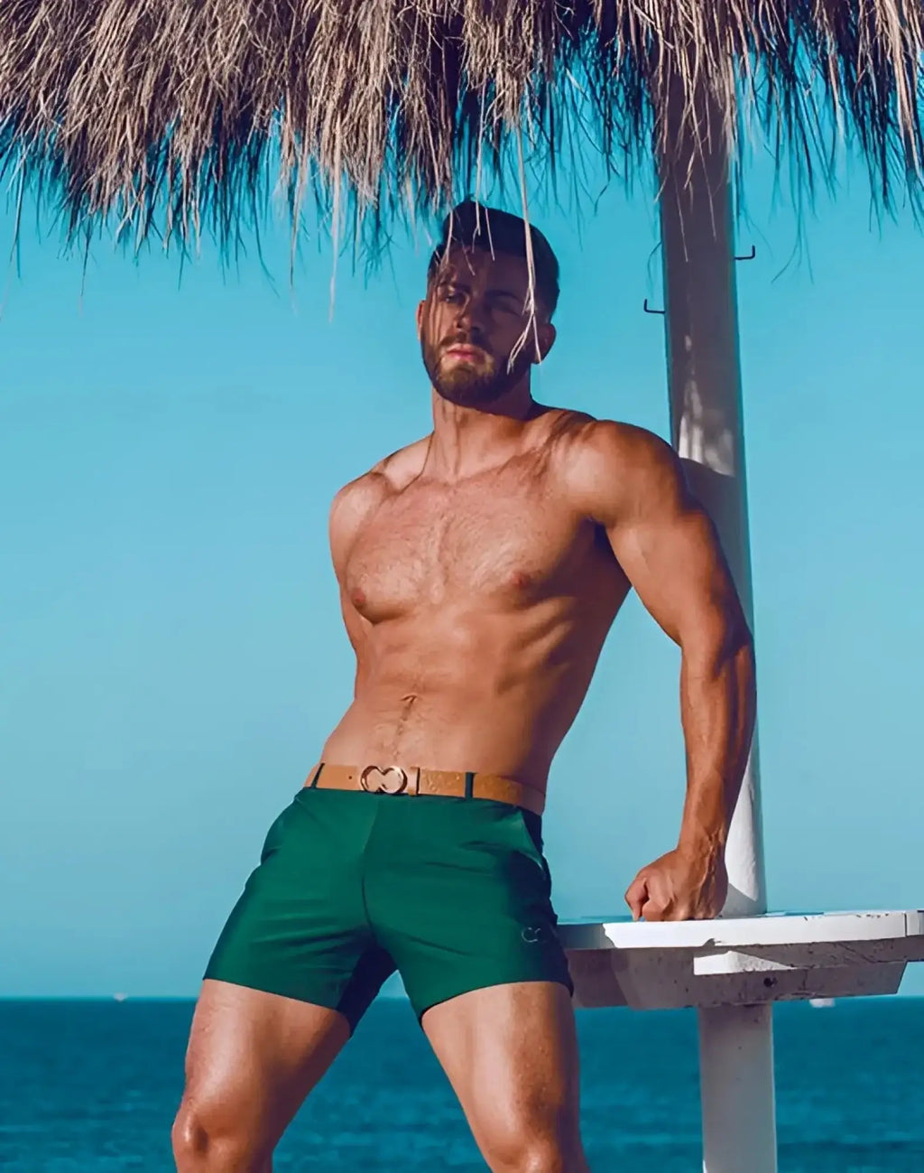 Green 2EROS Bondi swim trunks with a tan belt featuring a heart shaped buckle for stylish beachwear