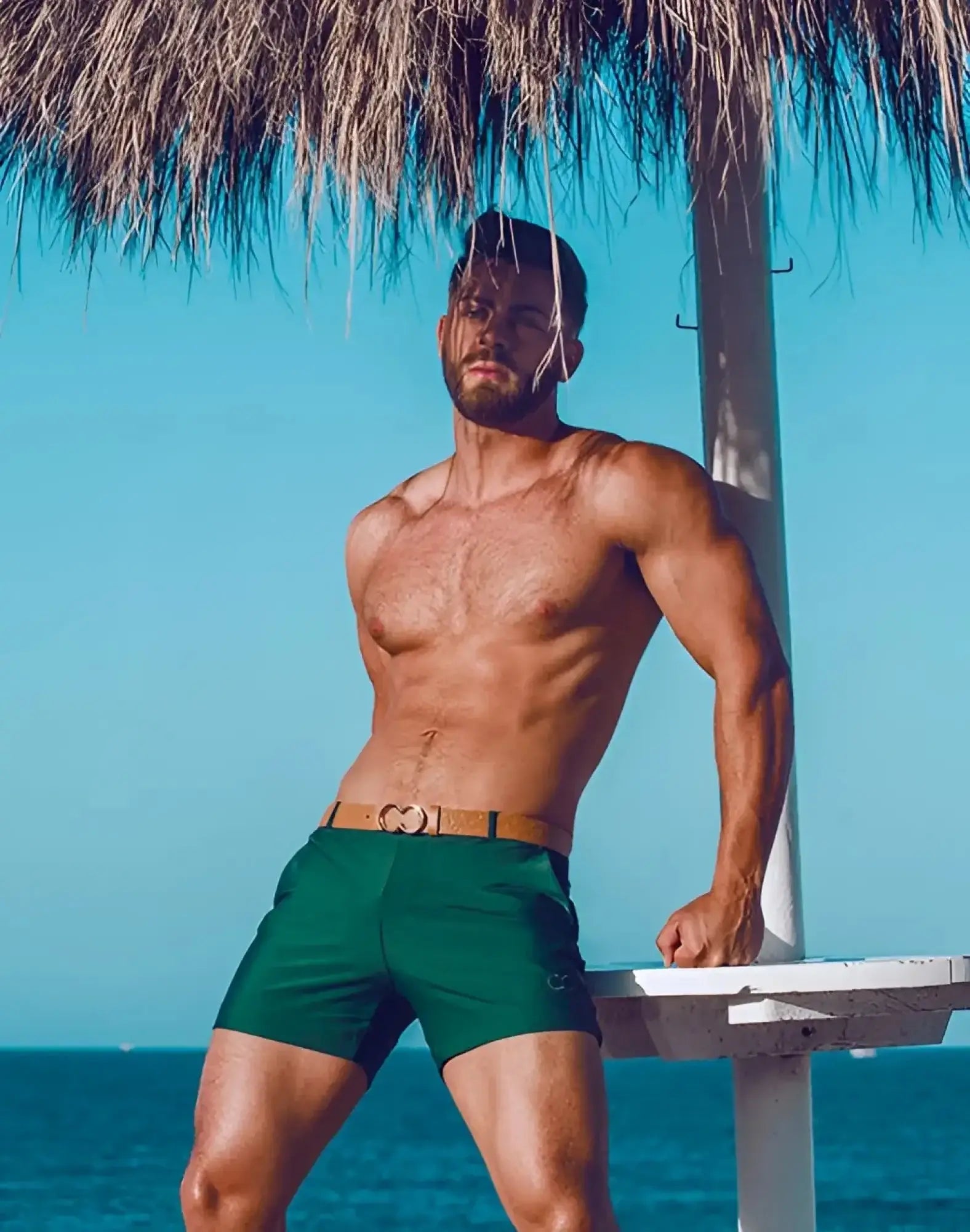 Green 2EROS Bondi swim trunks with a tan belt featuring a heart shaped buckle for stylish beachwear