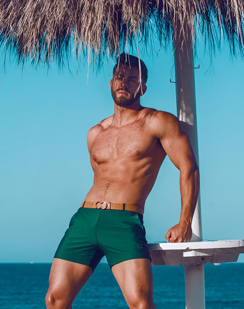 Green 2EROS Bondi swim trunks with a tan belt featuring a heart shaped buckle for stylish beachwear