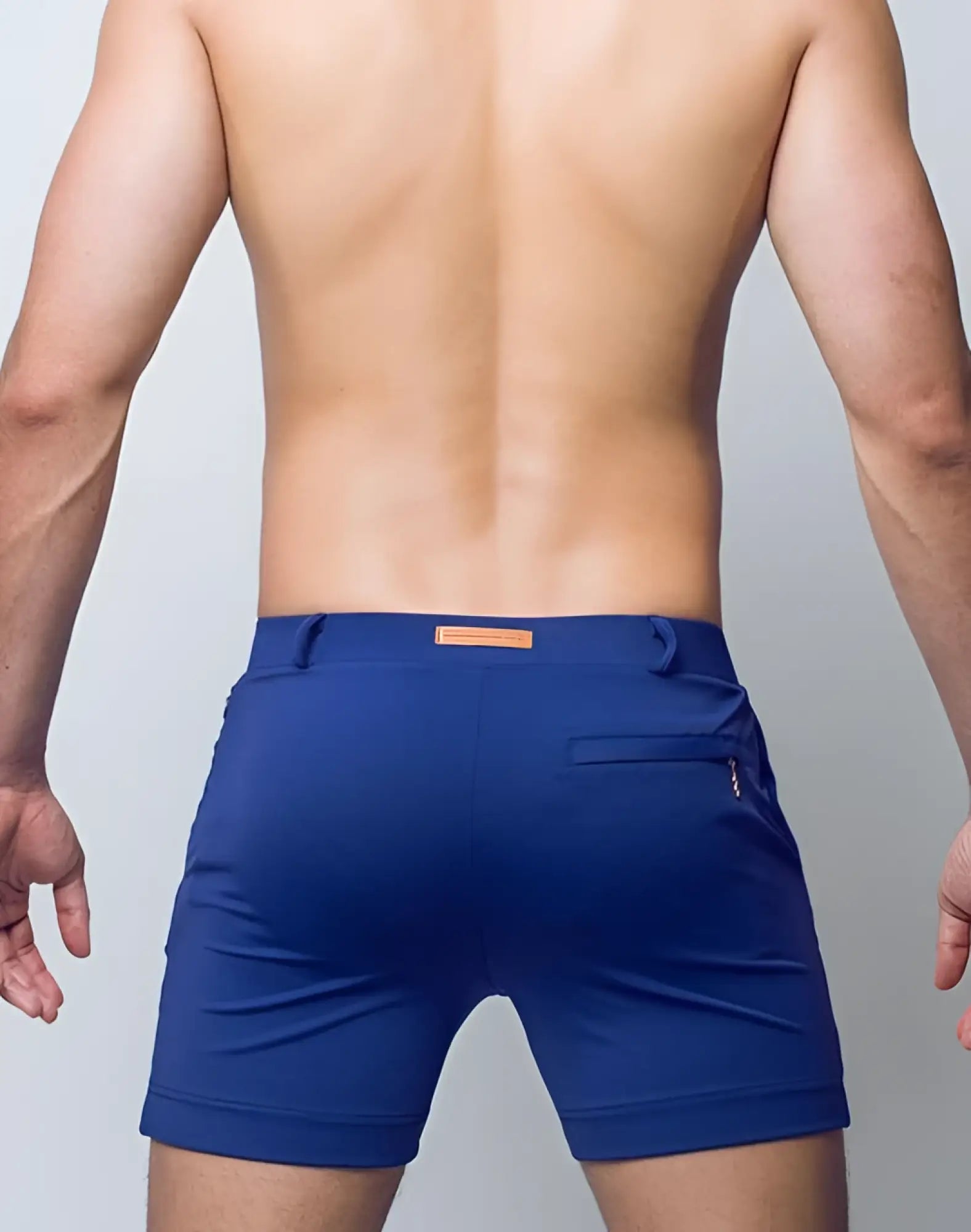Back view of 2eros bondi shorts series 3 navy featuring blue athletic material with orange waistband label and zip pocket
