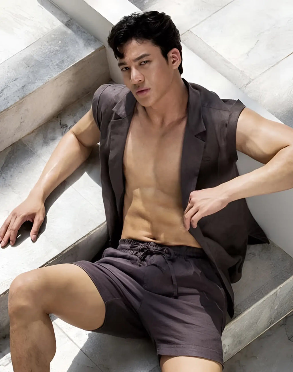 A man wearing dark gray 2EROS breezy 6 inch classic linen shorts and a sleeveless blazer