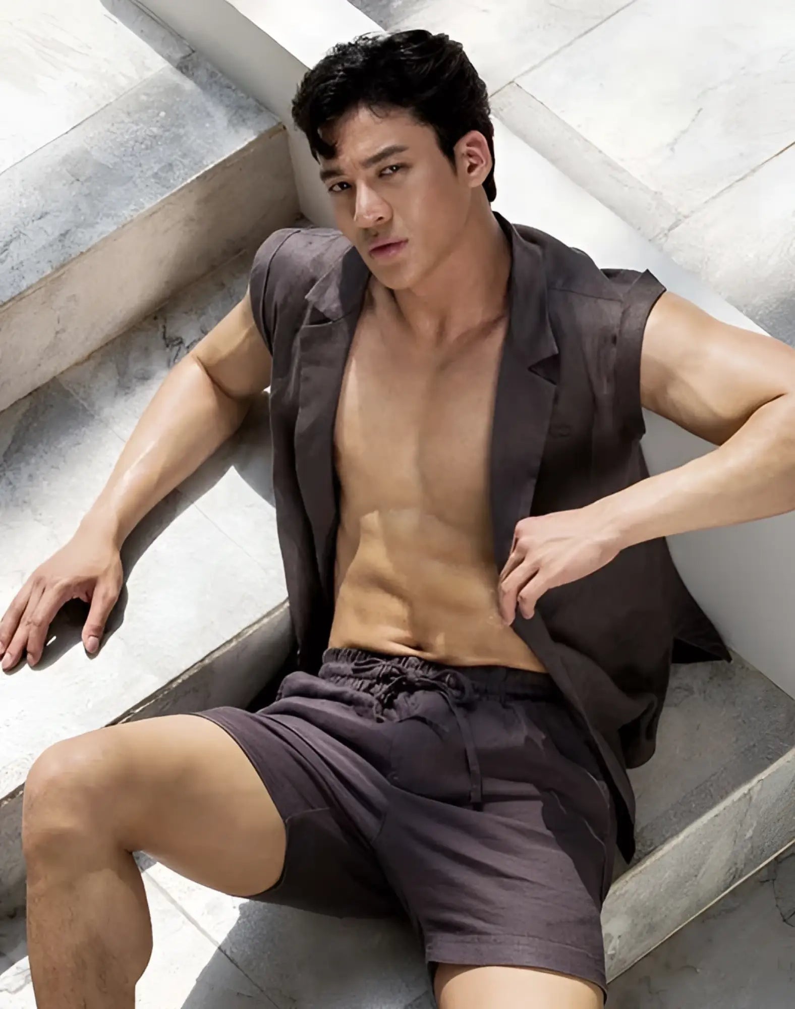 A man wearing dark gray 2EROS breezy 6 inch classic linen shorts and a sleeveless blazer