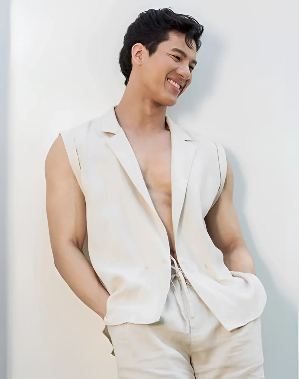 A man wearing a beige 2EROS breezy linen single button wrap vest with sleeveless blazer style and matching drawstring pants