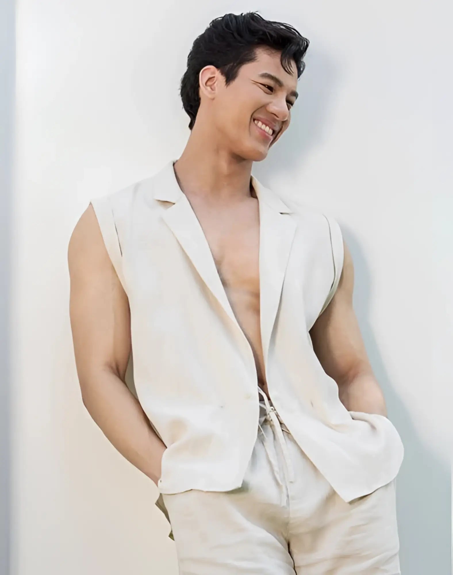 A man wearing a beige 2EROS breezy linen single button wrap vest with sleeveless blazer style and matching drawstring pants