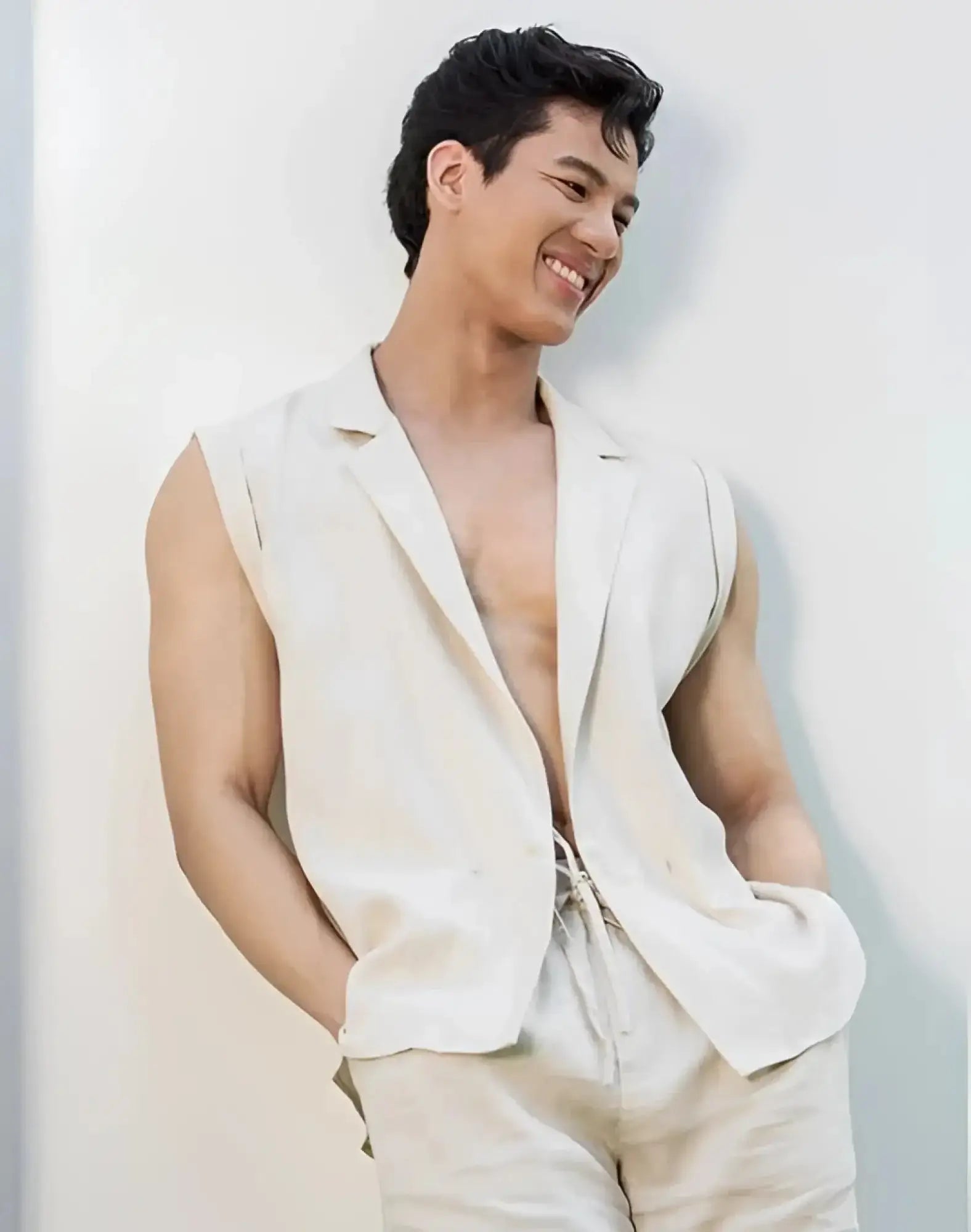 A man wearing a beige 2EROS breezy linen single button wrap vest with sleeveless blazer style and matching drawstring pants