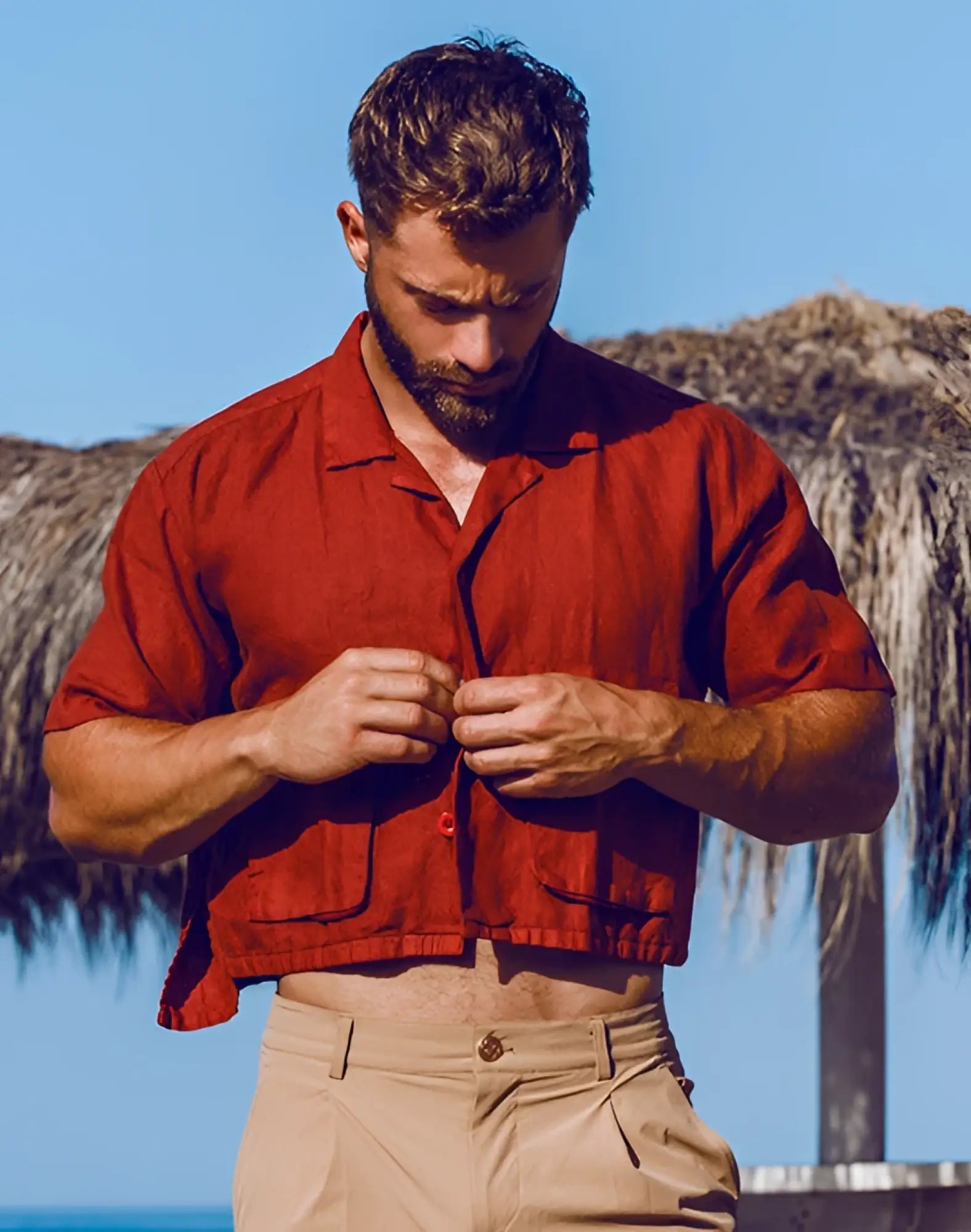 A man wearing a rust-colored 2EROS cropped linen shirt with short sleeves and two chest pockets in Bombay Brown