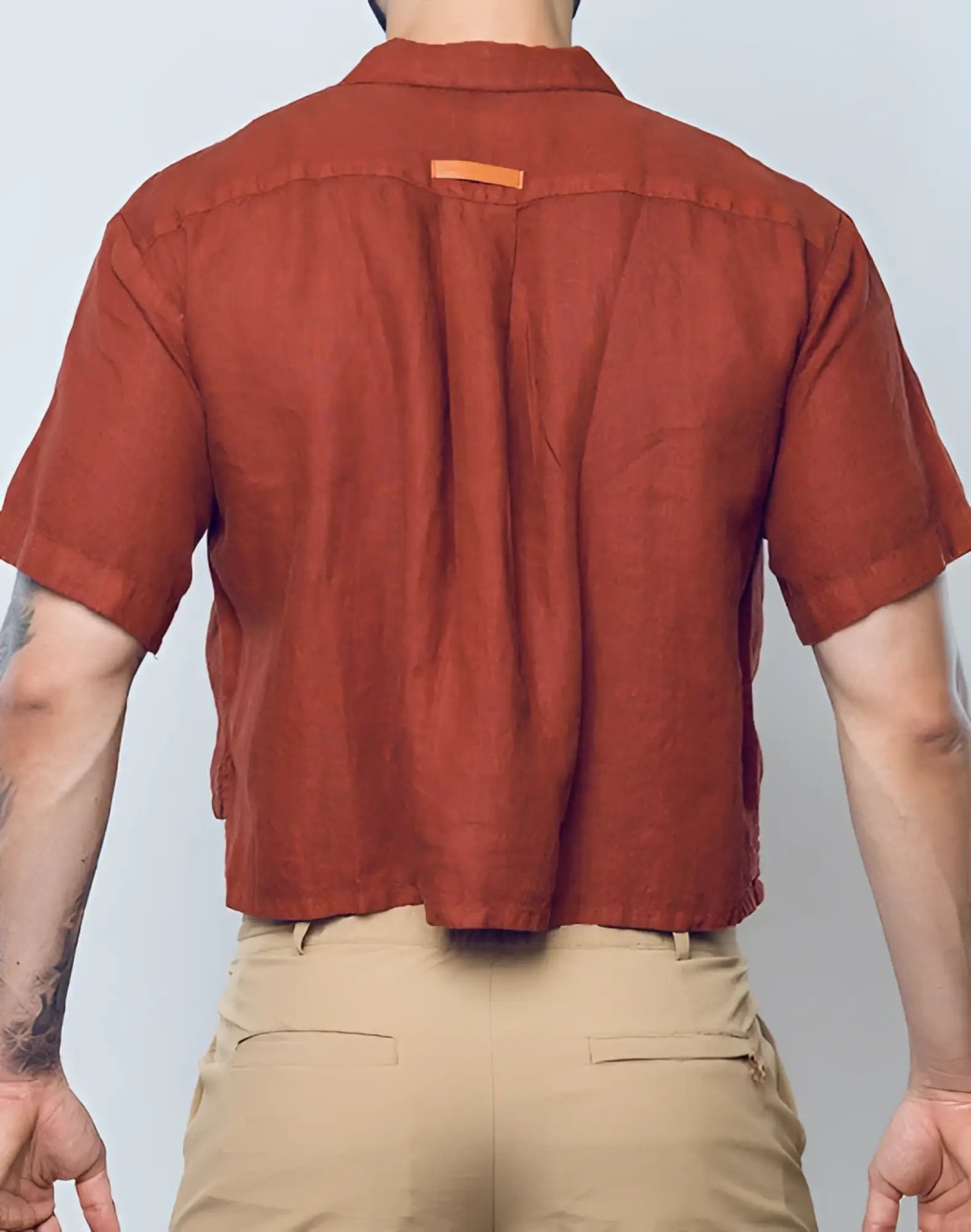 A rust-colored cropped short-sleeved 2EROS linen shirt with collar and subtle stitching details in Bombay Brown