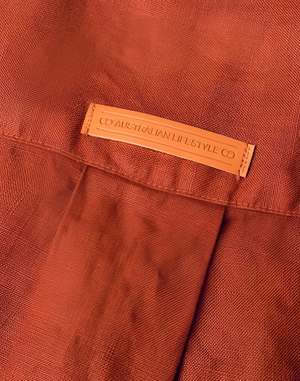 A tan leather label embossed with co australian lifestyle co stitched on the back of a 2eros cropped linen shirt bombay brown