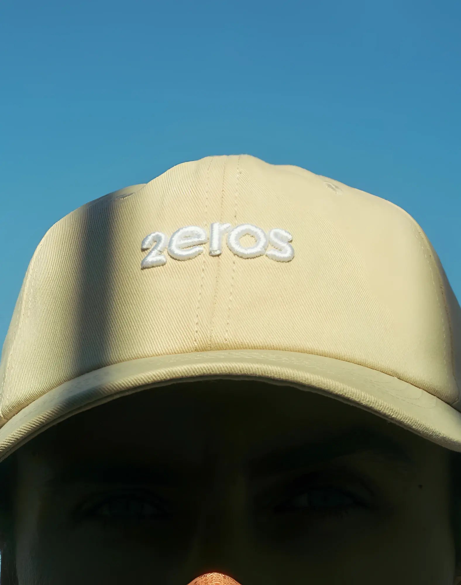 Beige 2EROS icon cap featuring a white embroidered 2eros logo in a classic baseball cap style