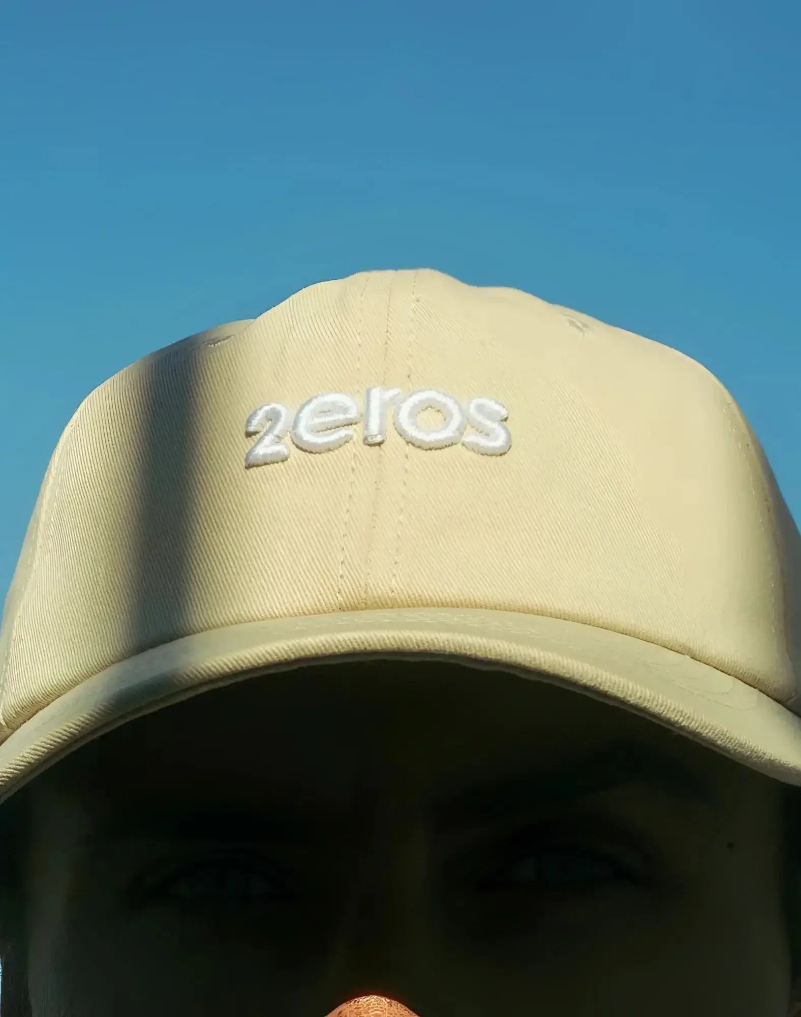 Beige 2EROS icon cap featuring a white embroidered 2eros logo in a classic baseball cap style