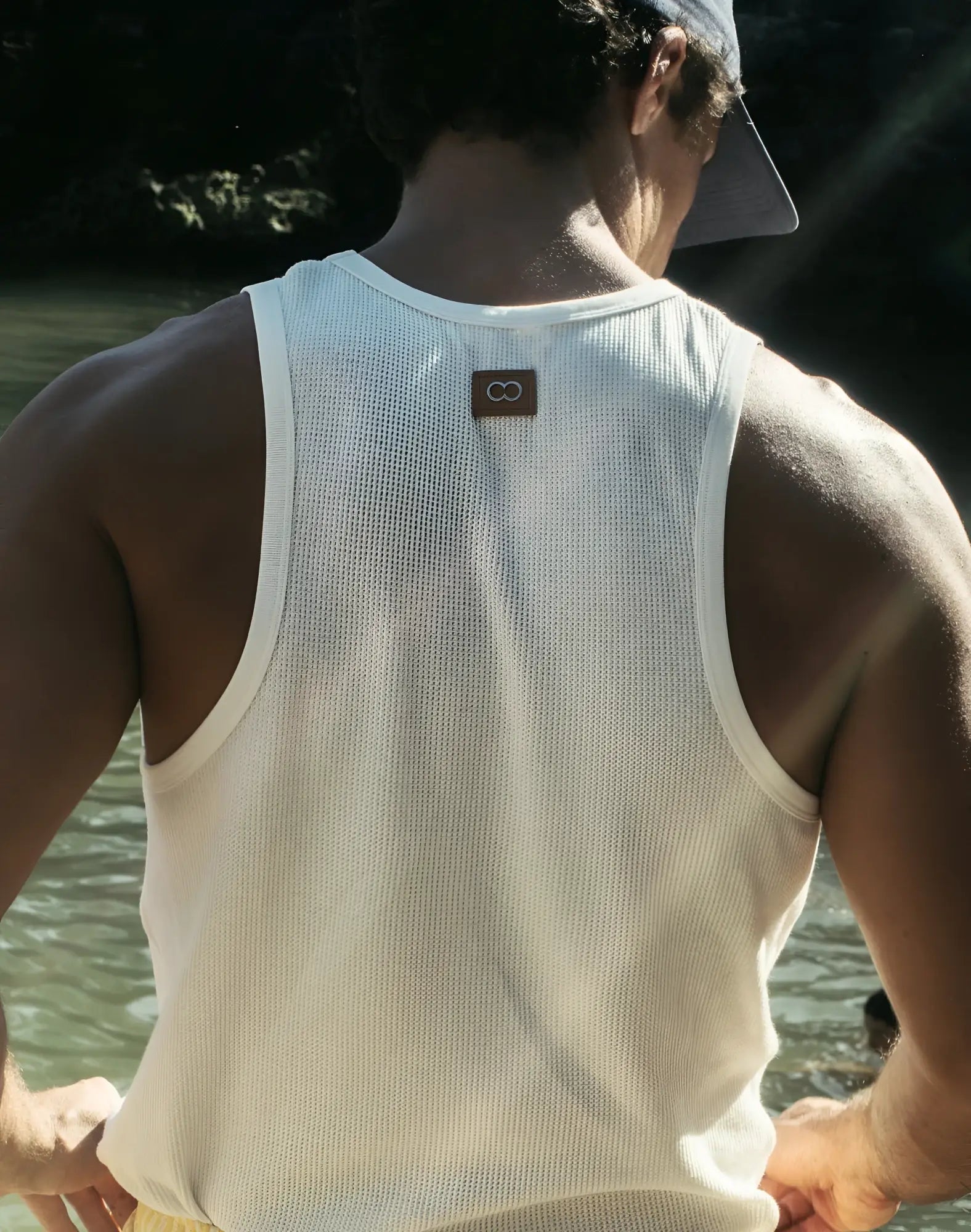 White ribbed 2EROS icon singlet tank top showing back with small brown rectangular logo patch on soft cotton fabric