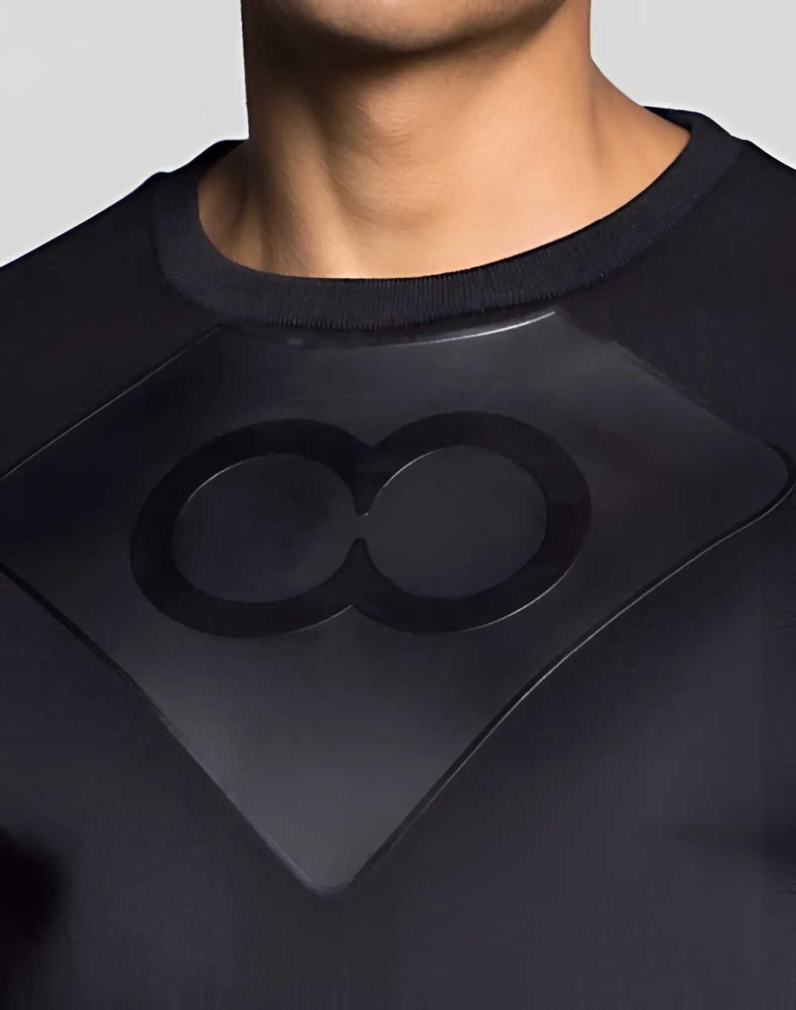 Black infinity symbol emblem on black textured fabric of the back side of 2EROS J50 BLK AKTIV short sweater