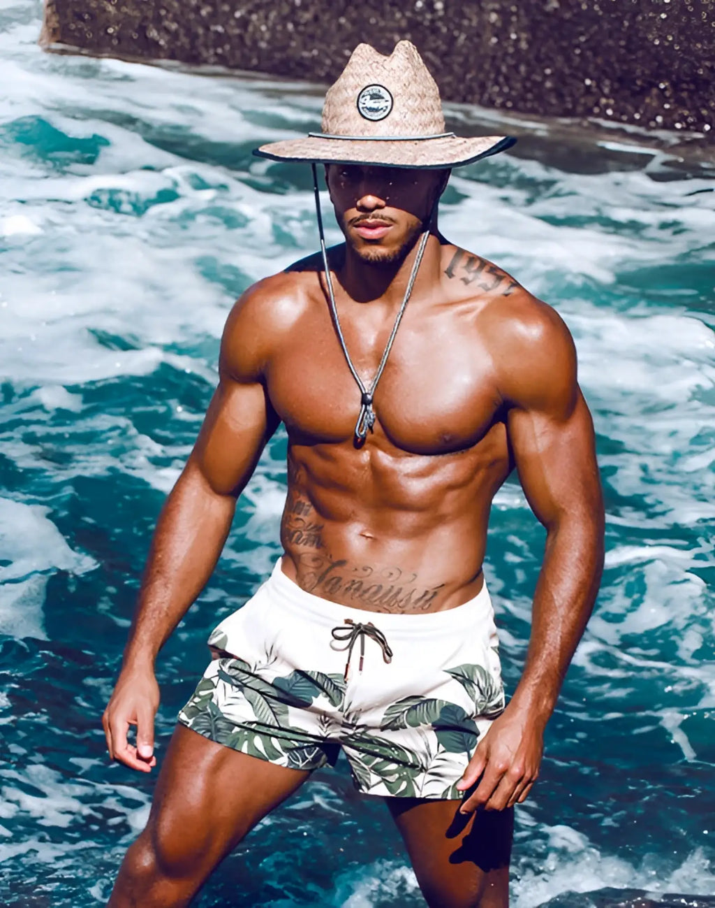 Beige straw hat with a circular logo on the front paired with 2eros printed bronte shorts exotica design