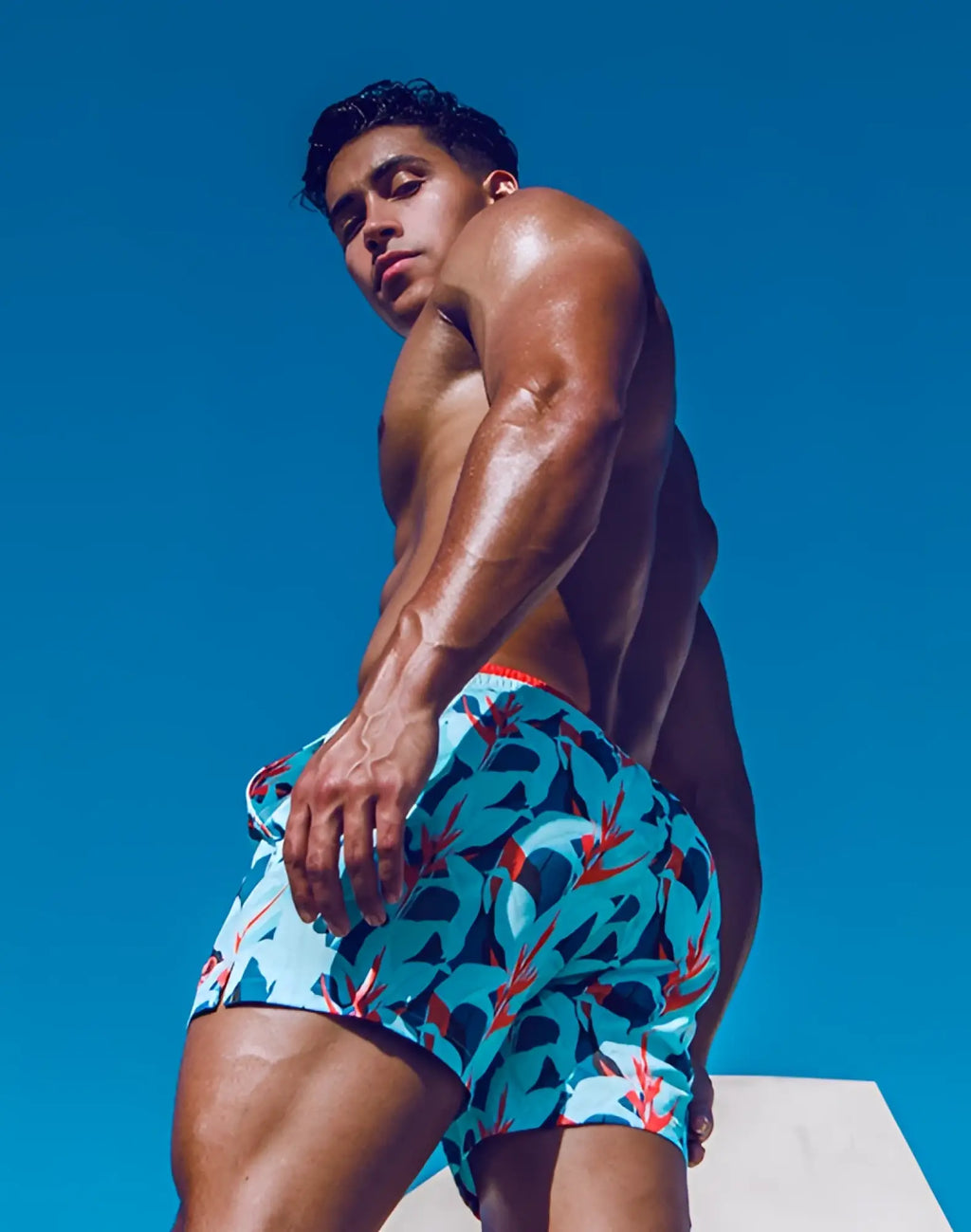 Blue 2EROS printed Byron swim trunks with a vibrant red and black tropical leaf pattern and an orange waistband