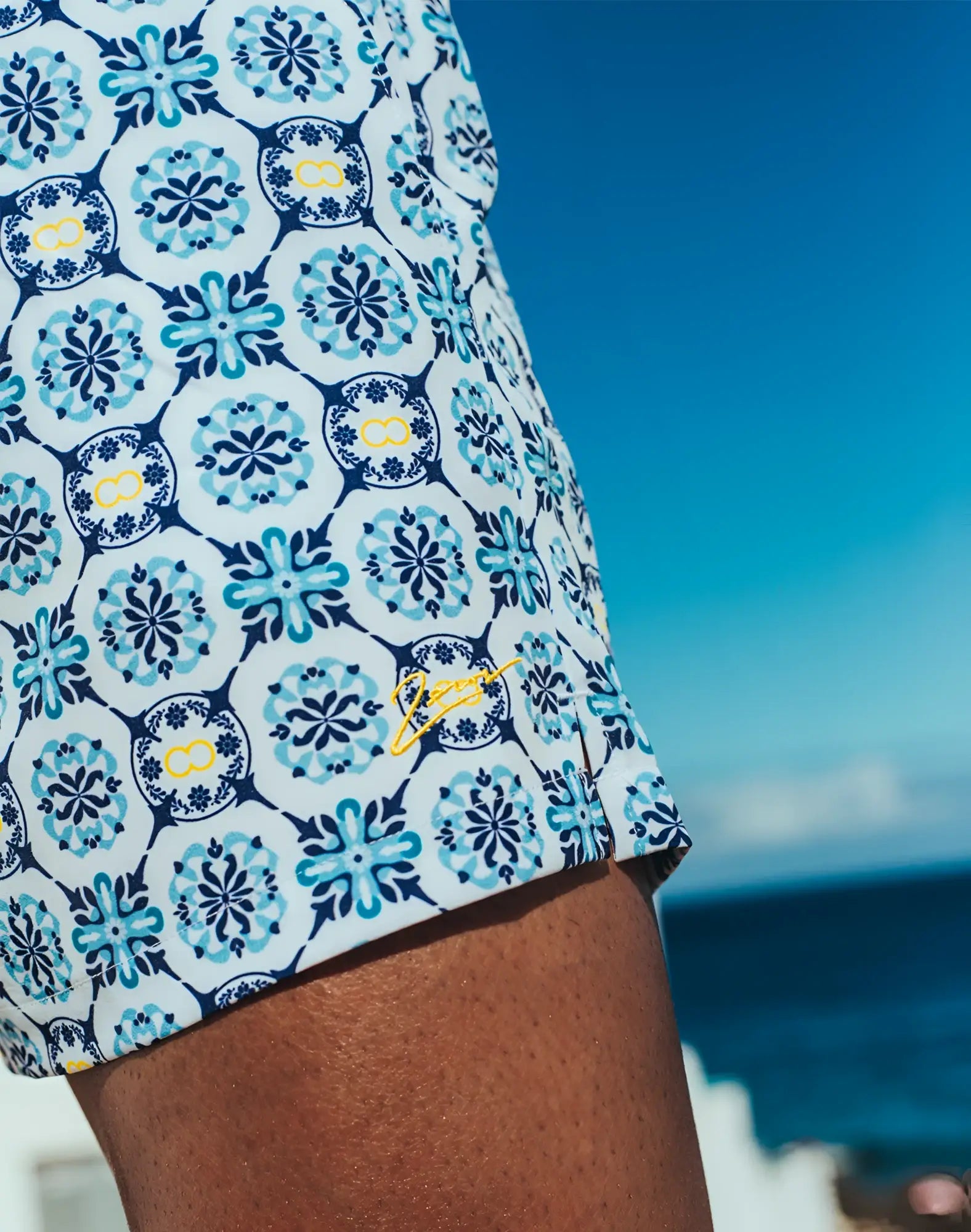 White 2eros printed byron swim trunks with navy blue floral medallions and yellow infinity symbols for mykonos beachwear