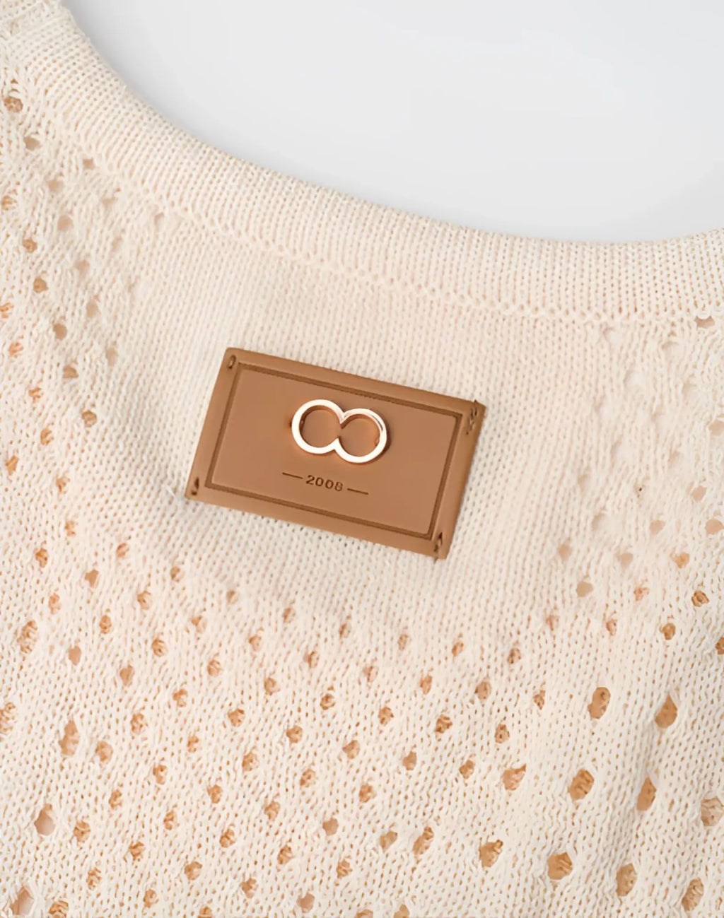 Beige knitted 2eros riviera singlet featuring a tan leather patch with an embroidered infinity symbol and year 2006