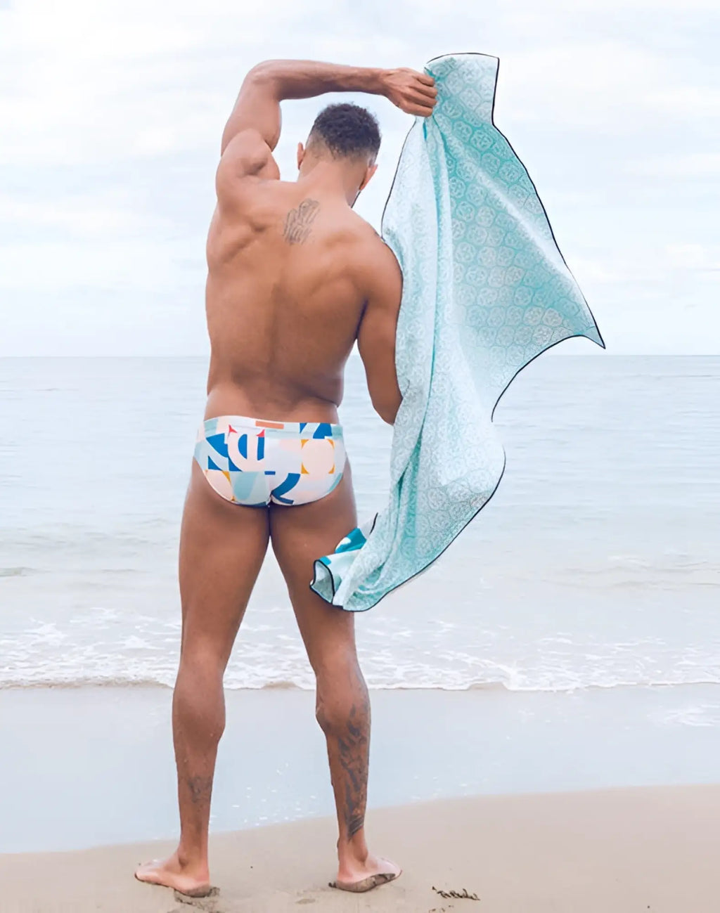 A light blue 2EROS sand-free beach towel with a subtle white geometric pattern and dark green trim called insignia turquoise