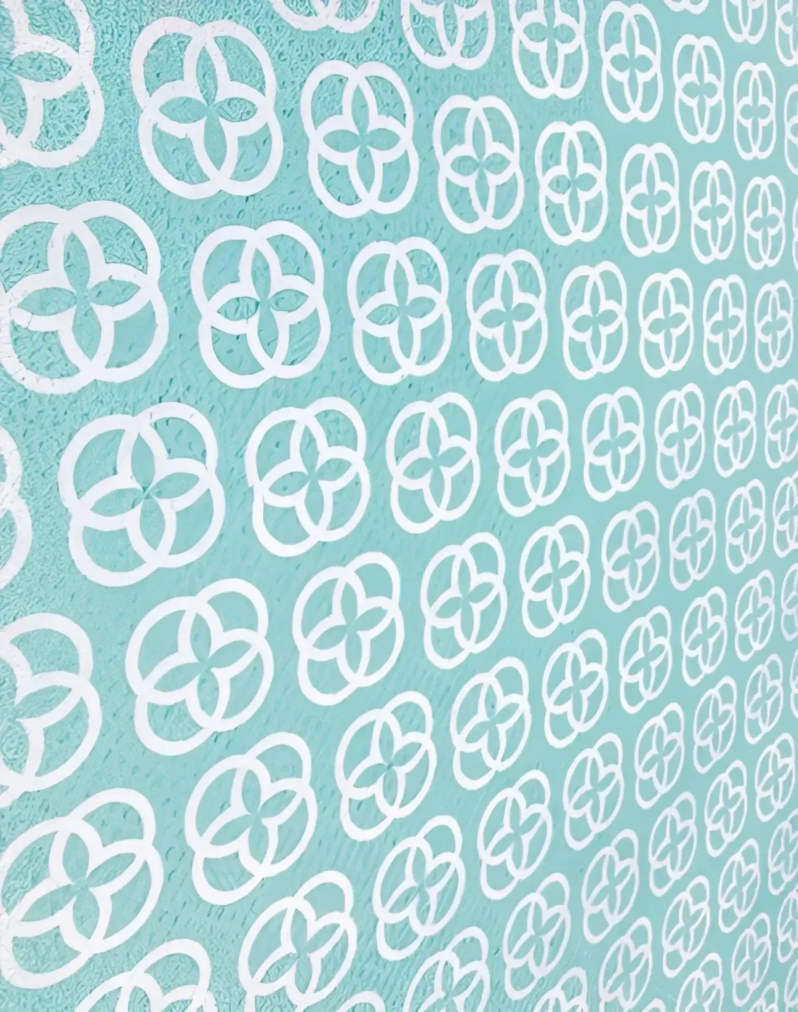 A soft mint green 2eros sand-free beach towel with white quatrefoil pattern designed for beach use