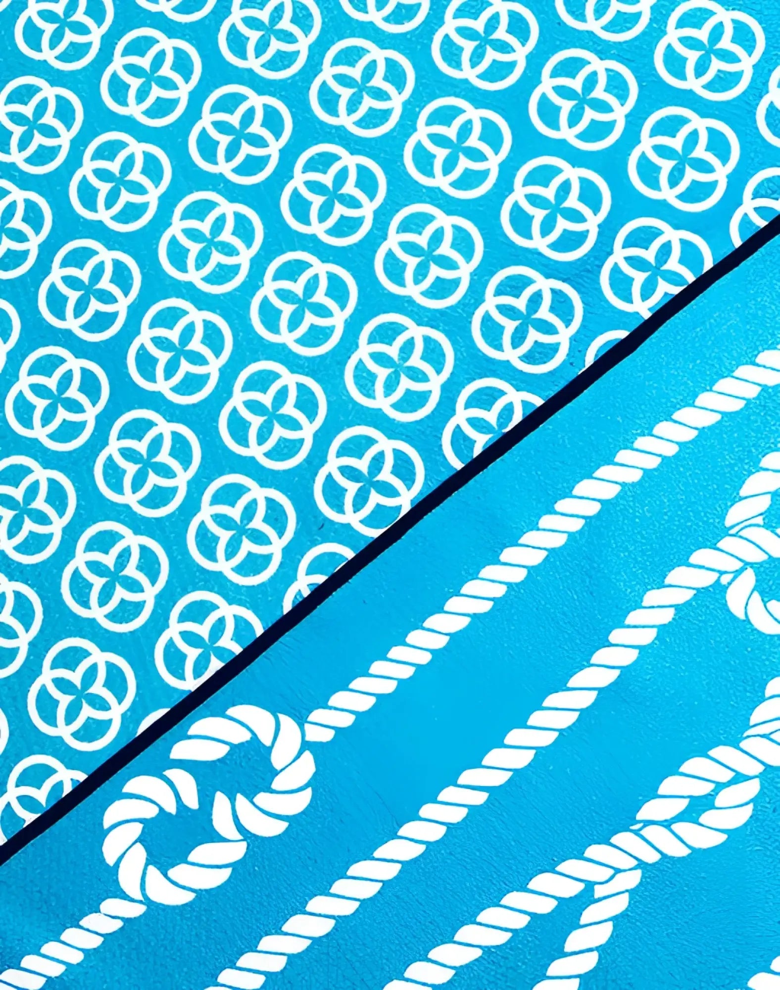 A vibrant turquoise 2EROS sand-free beach towel with bold white interlocking circles and rope motifs design