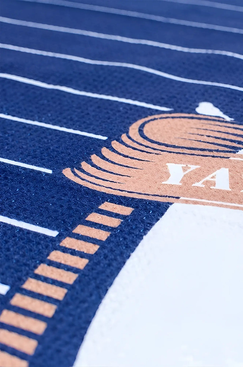 Blue and white striped 2eros sand free beach towel with copper ya logo in ornate design for yacht club use