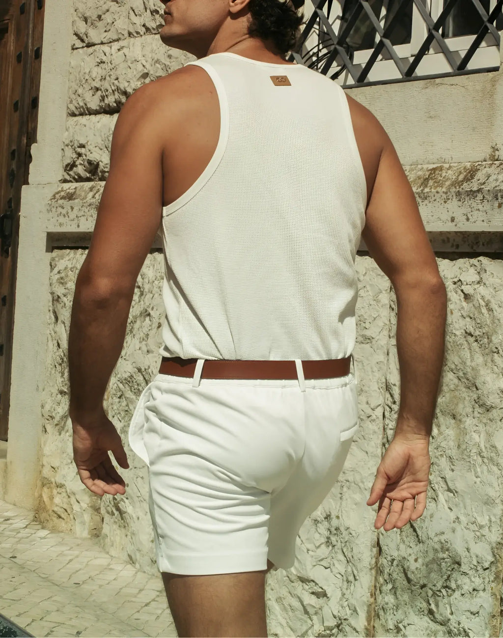 White ribbed tank top with small brown leather patch at neckline paired with 2EROS Trinity Shorts in white