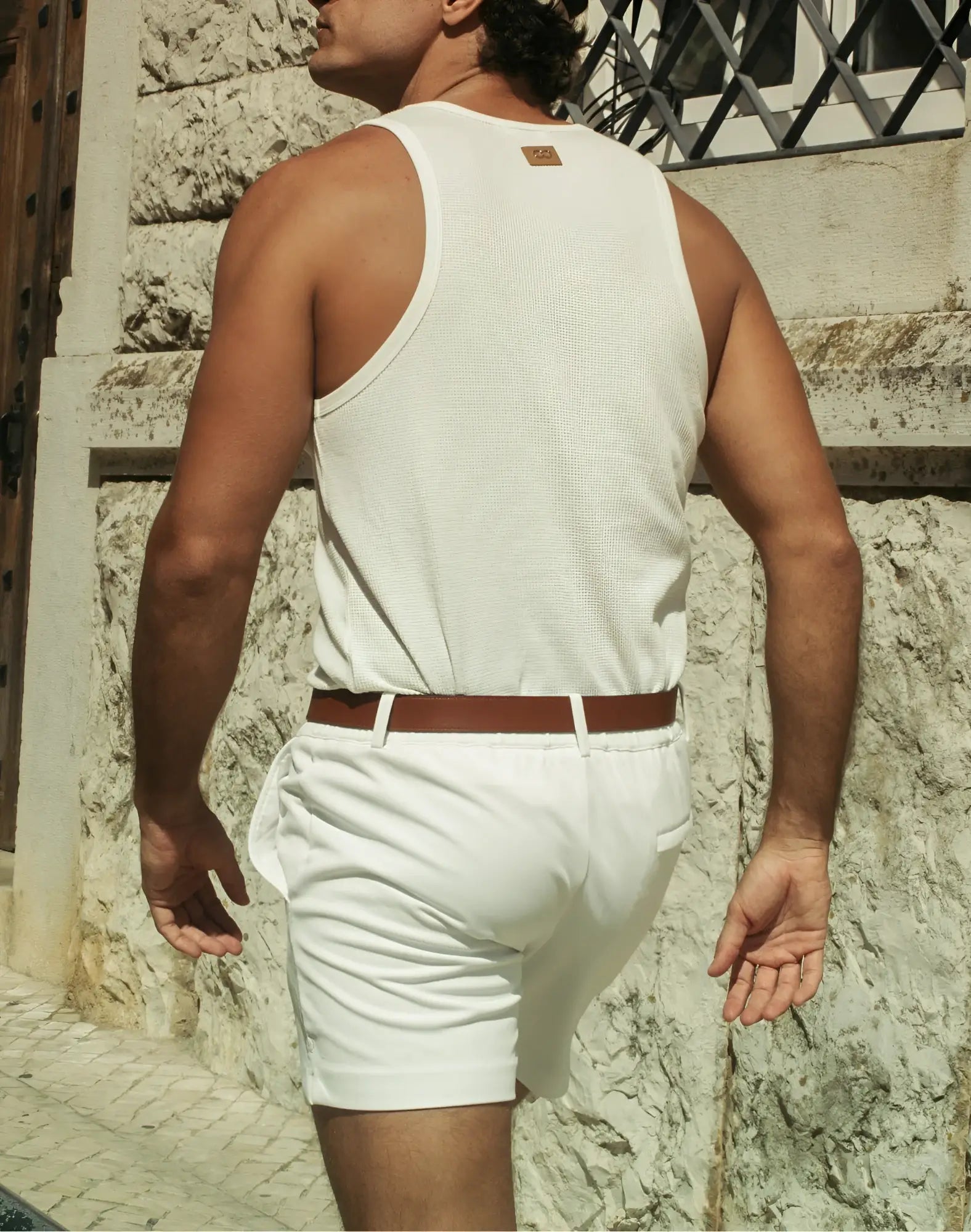 White ribbed tank top with small brown leather patch at neckline paired with 2EROS Trinity Shorts in white