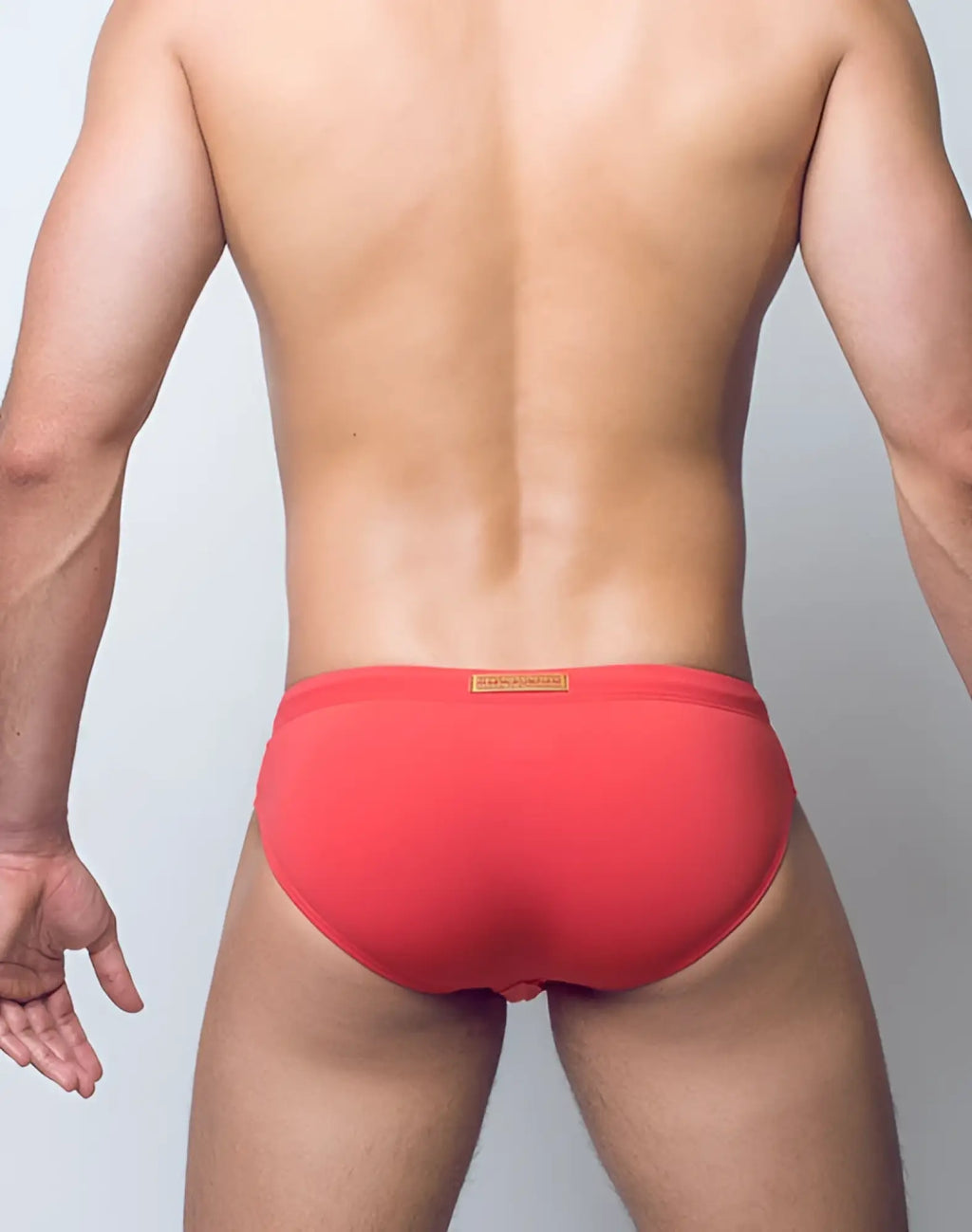 Red 2eros v10 core series 2 swimwear briefs with a coral hue and a small orange label at the waistband